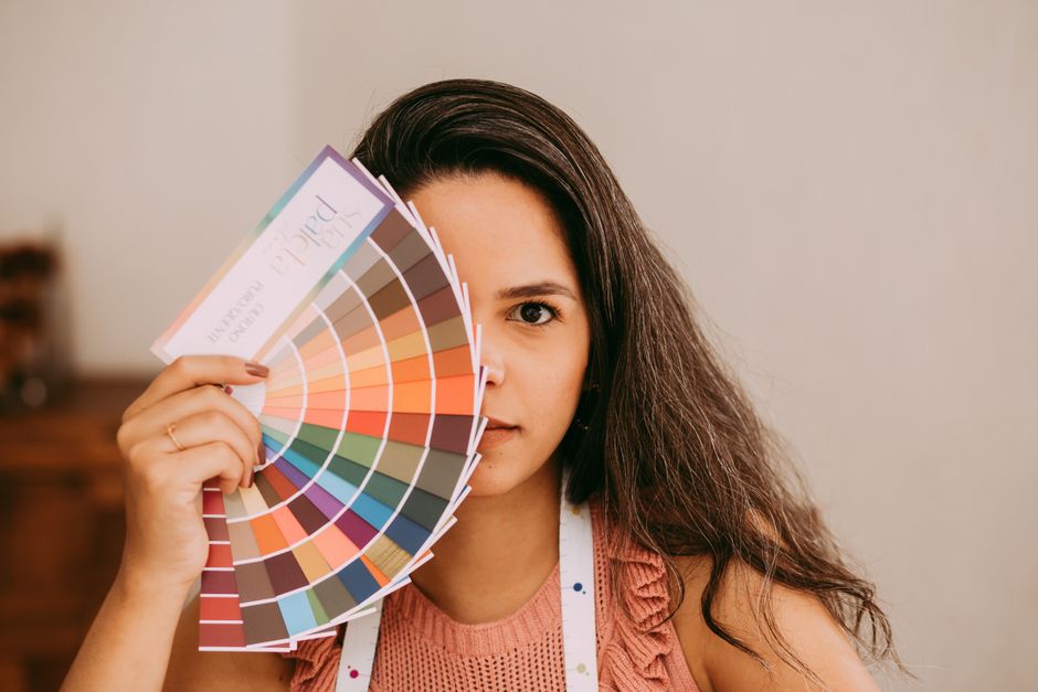 A woman holds a colorful palette, highlighting creative design and artistry.